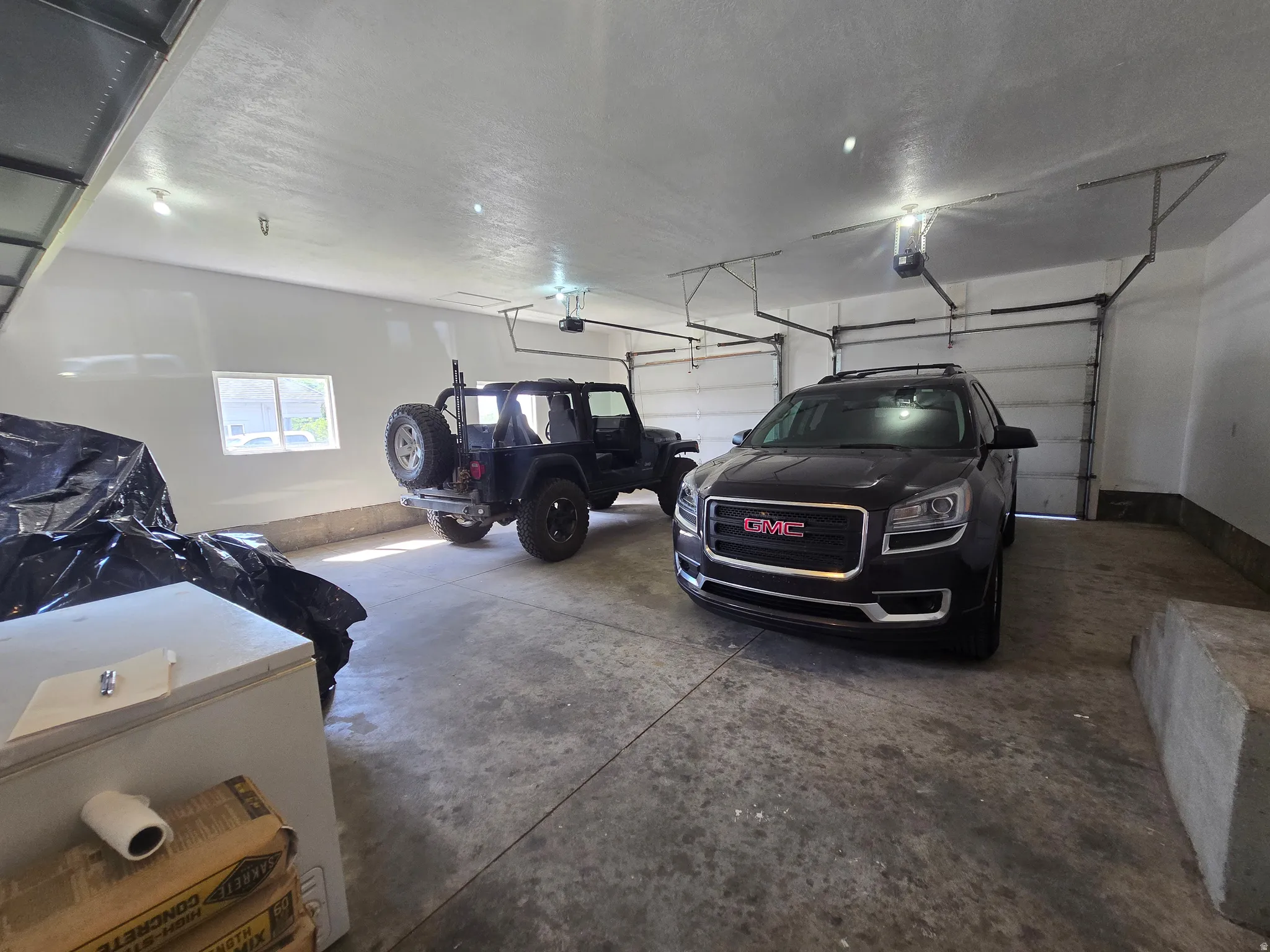 Attached two-car garage featuring a concrete floor, white walls, and overhead lighting