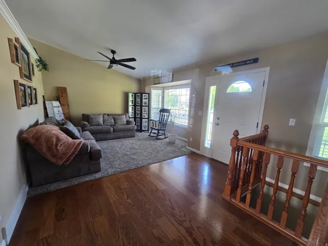 Entryway featuring rich wood-finish flooring, a white paneled front door with an arched transom window, and a wood baluster railing
