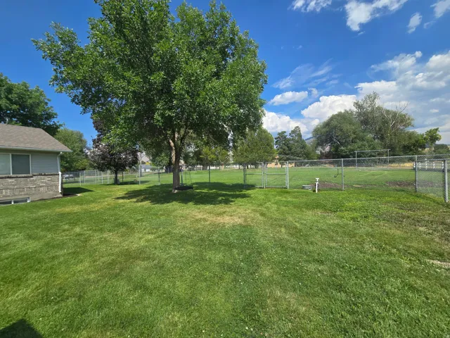 Expansive green lawn featuring mature trees providing ample shade