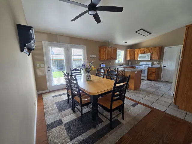 Kitchen and dining area featuring warm wood-finish cabinetry, white appliances, and a central island