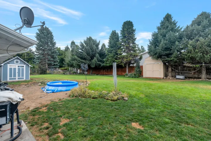 Expansive backyard featuring a manicured lawn, established landscaping, and mature trees