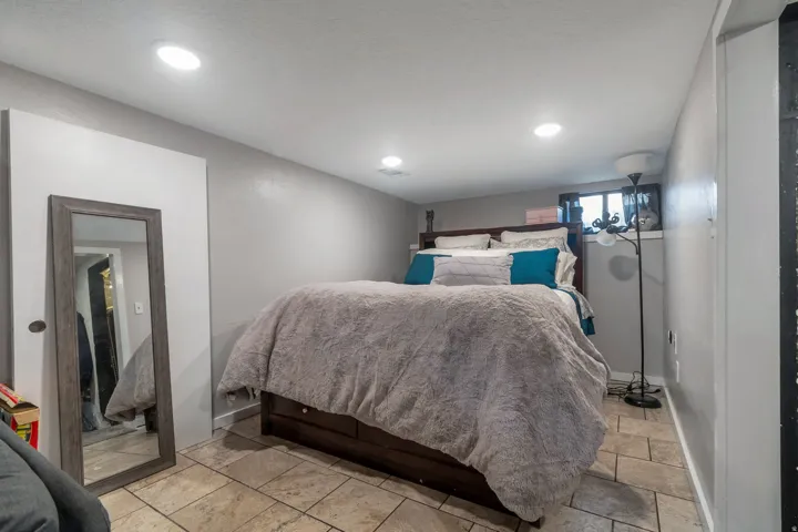 Recessed ceiling lighting illuminates a room featuring light-toned tile flooring and painted walls
