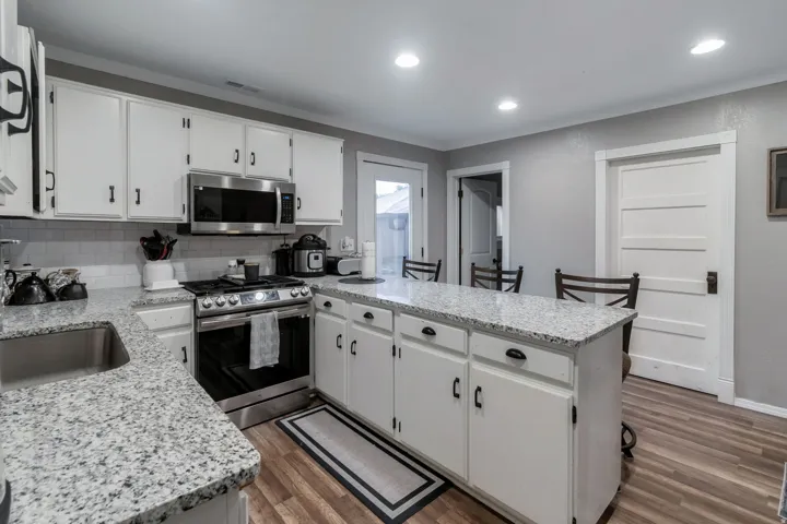 Bright kitchen featuring granite countertops and white cabinetry