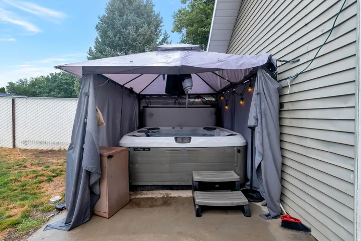 Outdoor spa area featuring a gray gazebo, string lighting, and direct access to the exterior siding