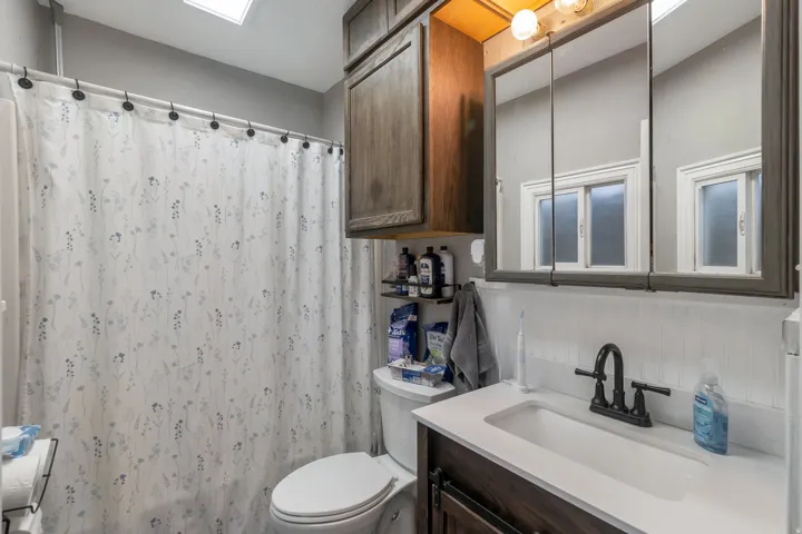Bathroom featuring a white integrated sink with a matte black faucet, dark wood-finish vanity, and a mirrored medicine cabinet