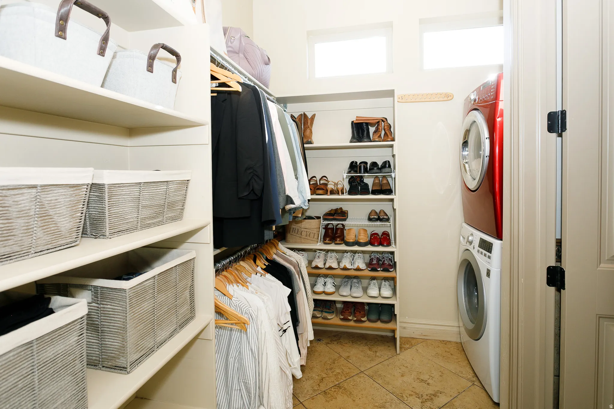 Integrated laundry area featuring a stacked washer and dryer, tile flooring, built-in shelving, and transom windows
