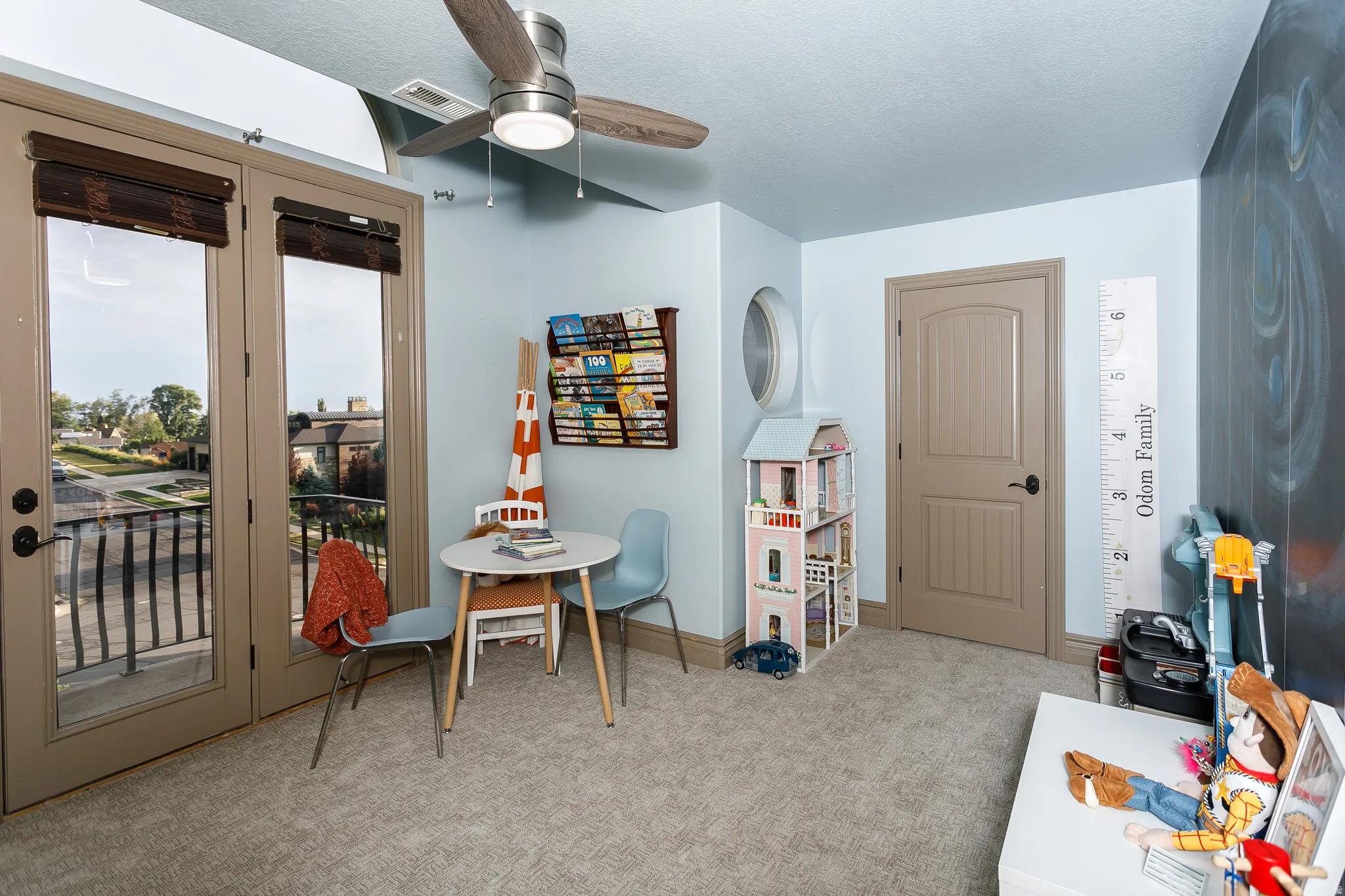Room featuring light-colored carpet flooring, a ceiling fan with integrated lighting, and a neutral-toned door with dark hardware
