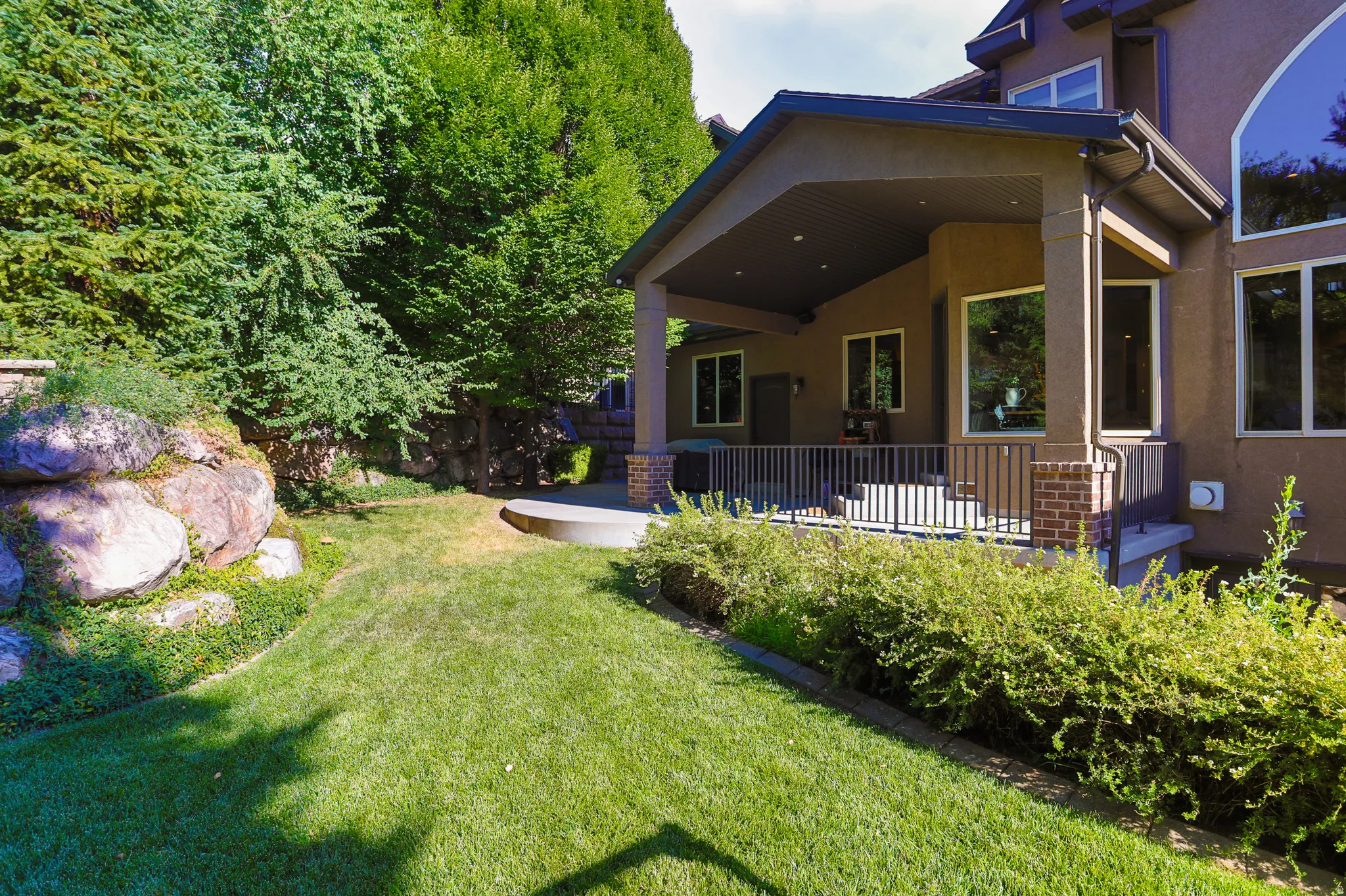 Expansive green lawn with mature trees and natural rock formations