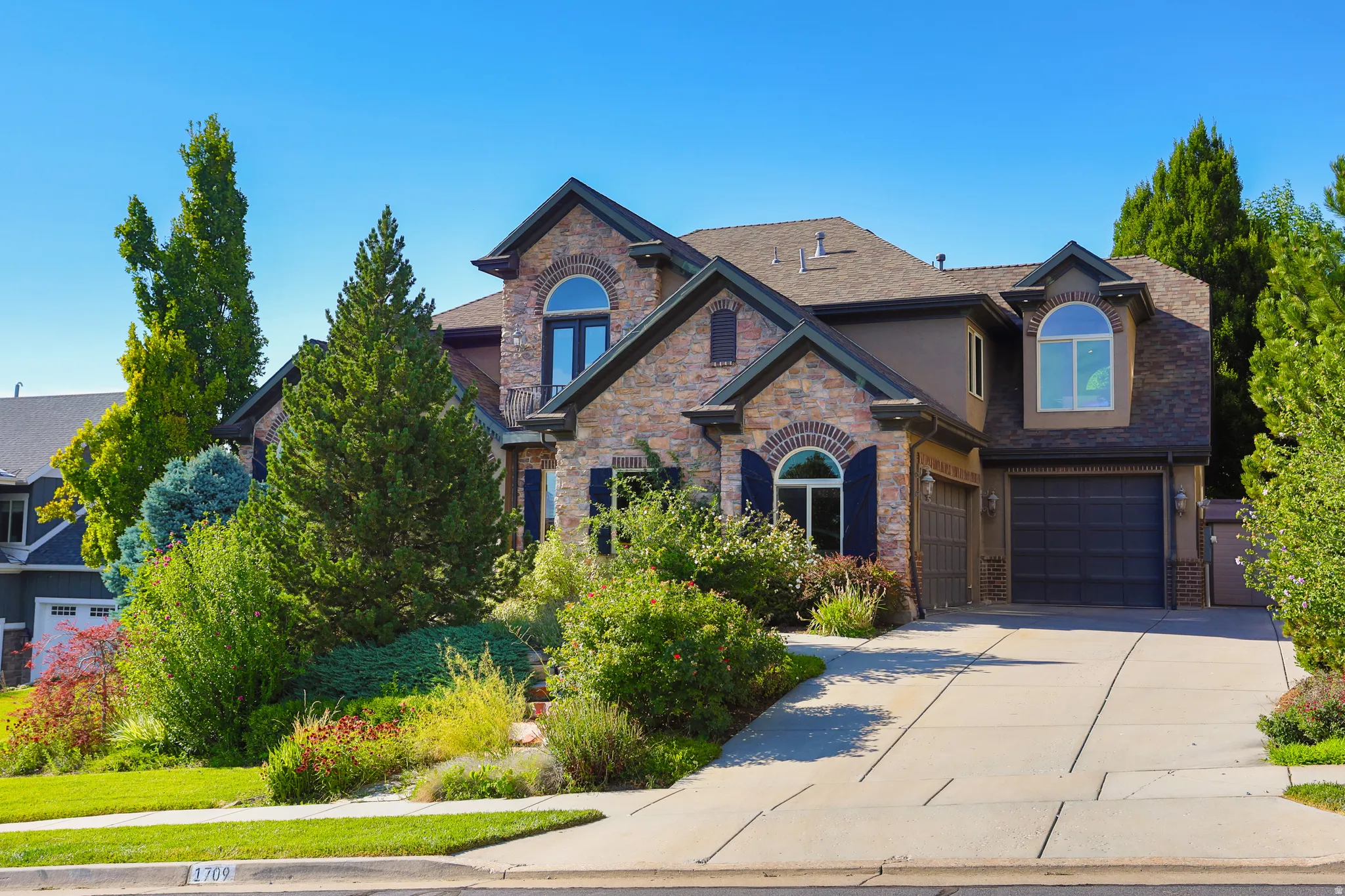 Stone and stucco exterior featuring multiple gables and arched windows