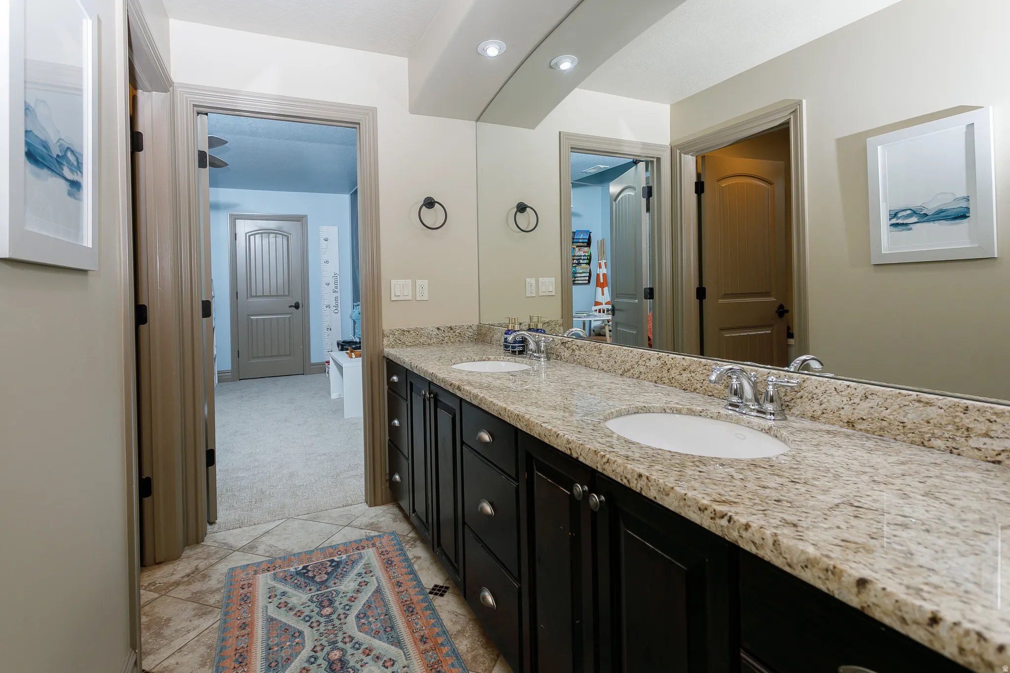 Double vanity featuring dark wood cabinetry, light speckled countertops, and undermount sinks
