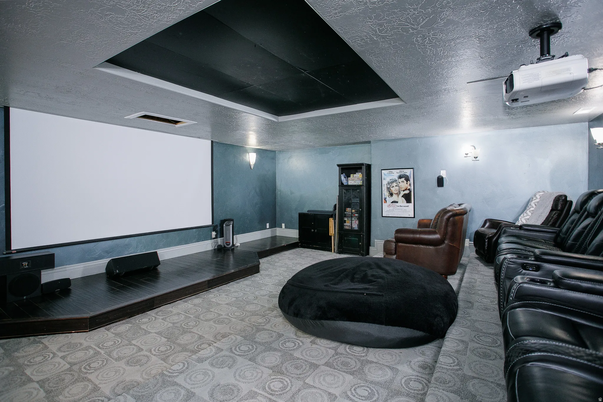 Dedicated media room featuring a large projection screen and elevated wood-finish platform
