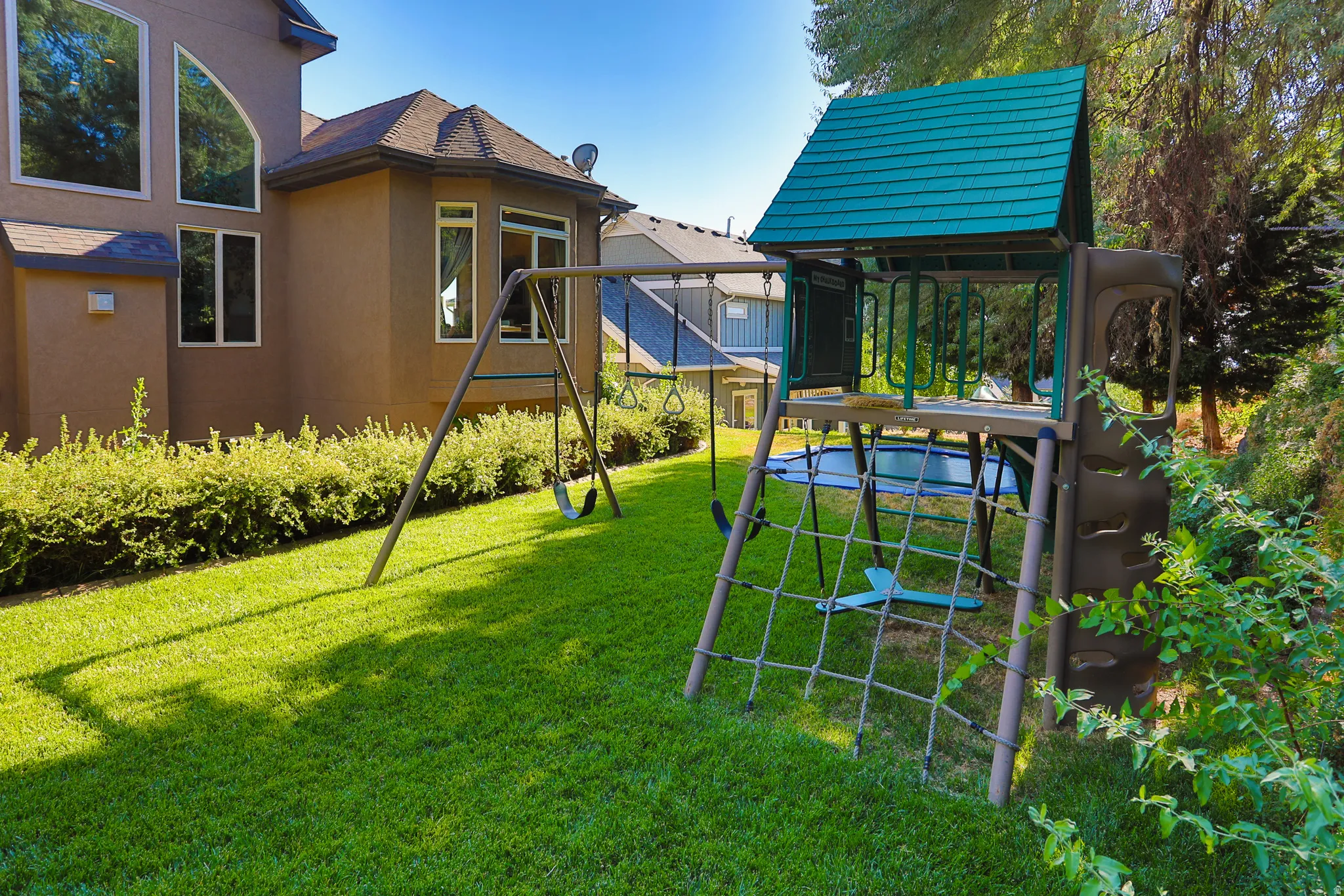 Expansive green lawn featuring a swing set and multi-level play structure