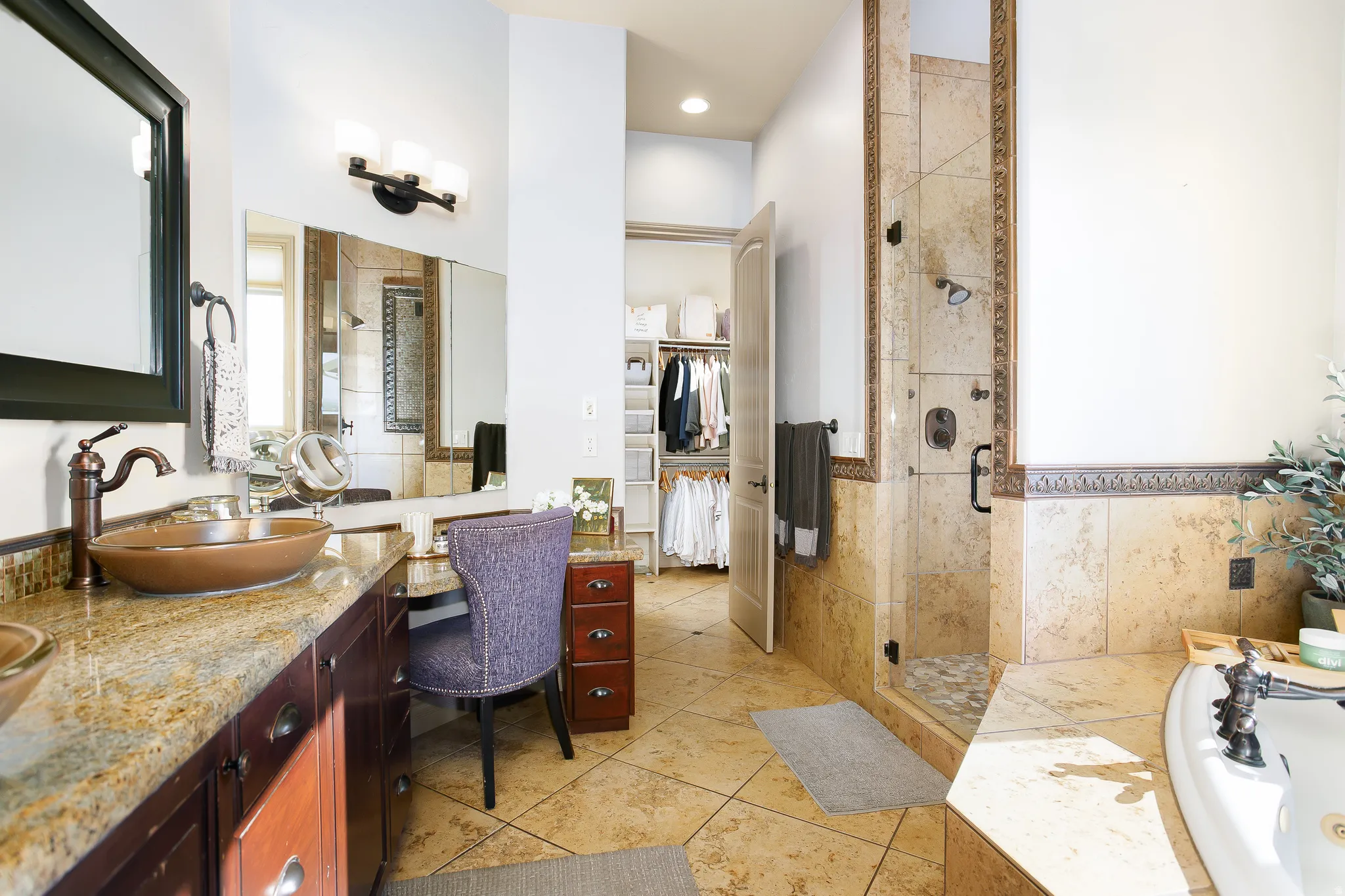 Bathroom featuring a built-in vanity with a granite countertop and vessel sink, a tiled shower with a glass enclosure, a built-in bathtub, and a closet with custom organizational shelving