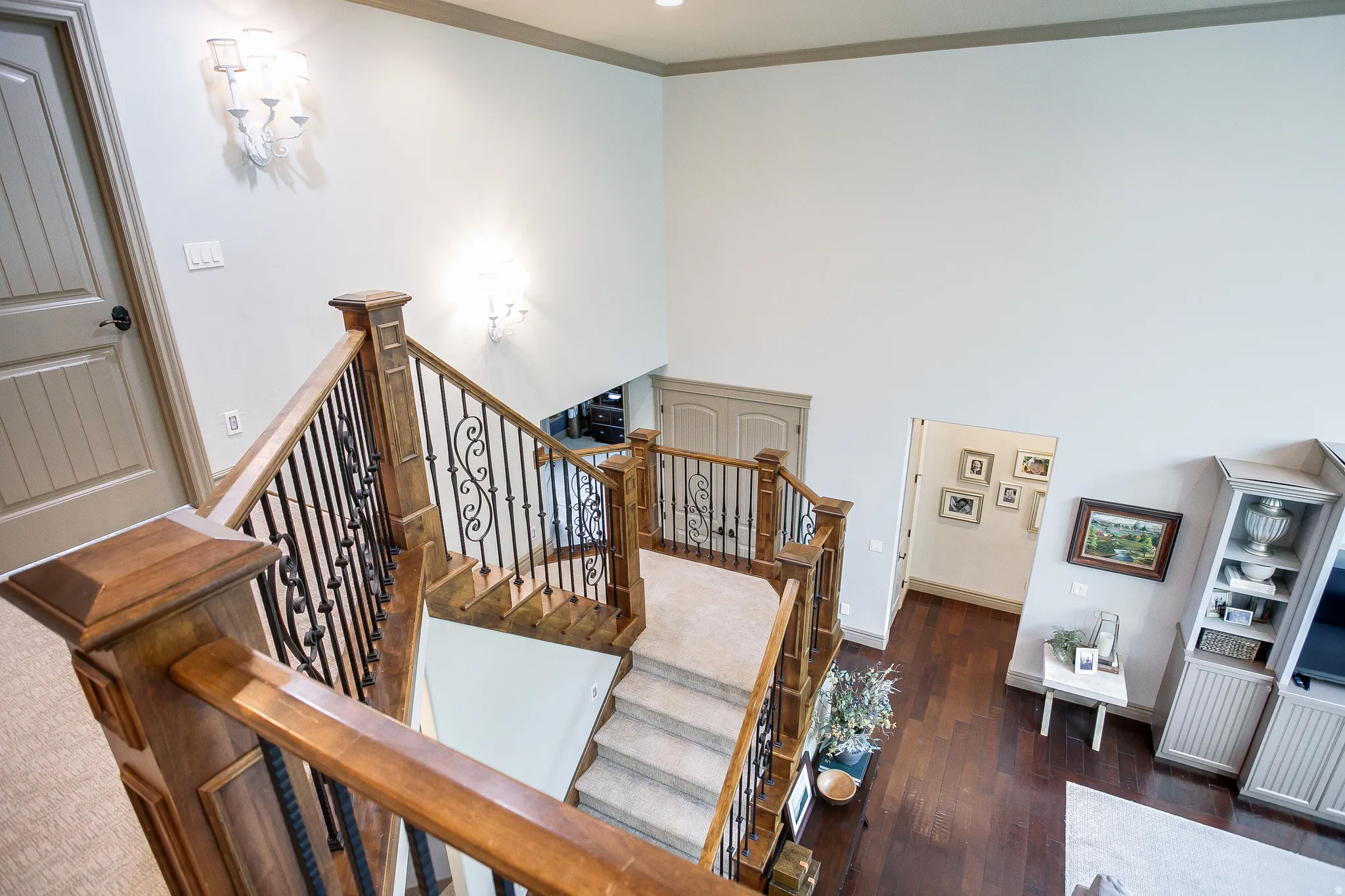 Grand staircase featuring wood-finish handrails and decorative wrought iron balusters