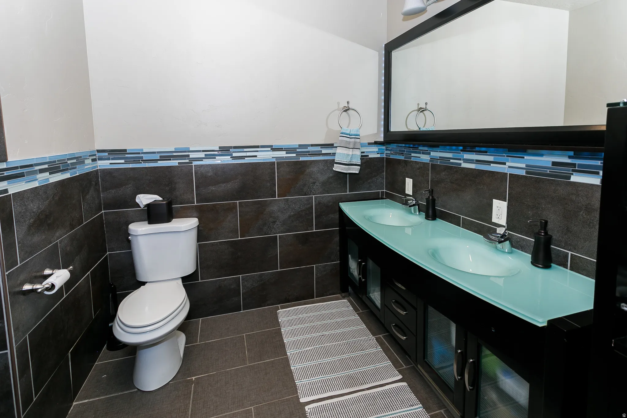 Dual basin vanity with a translucent countertop and sleek black cabinetry