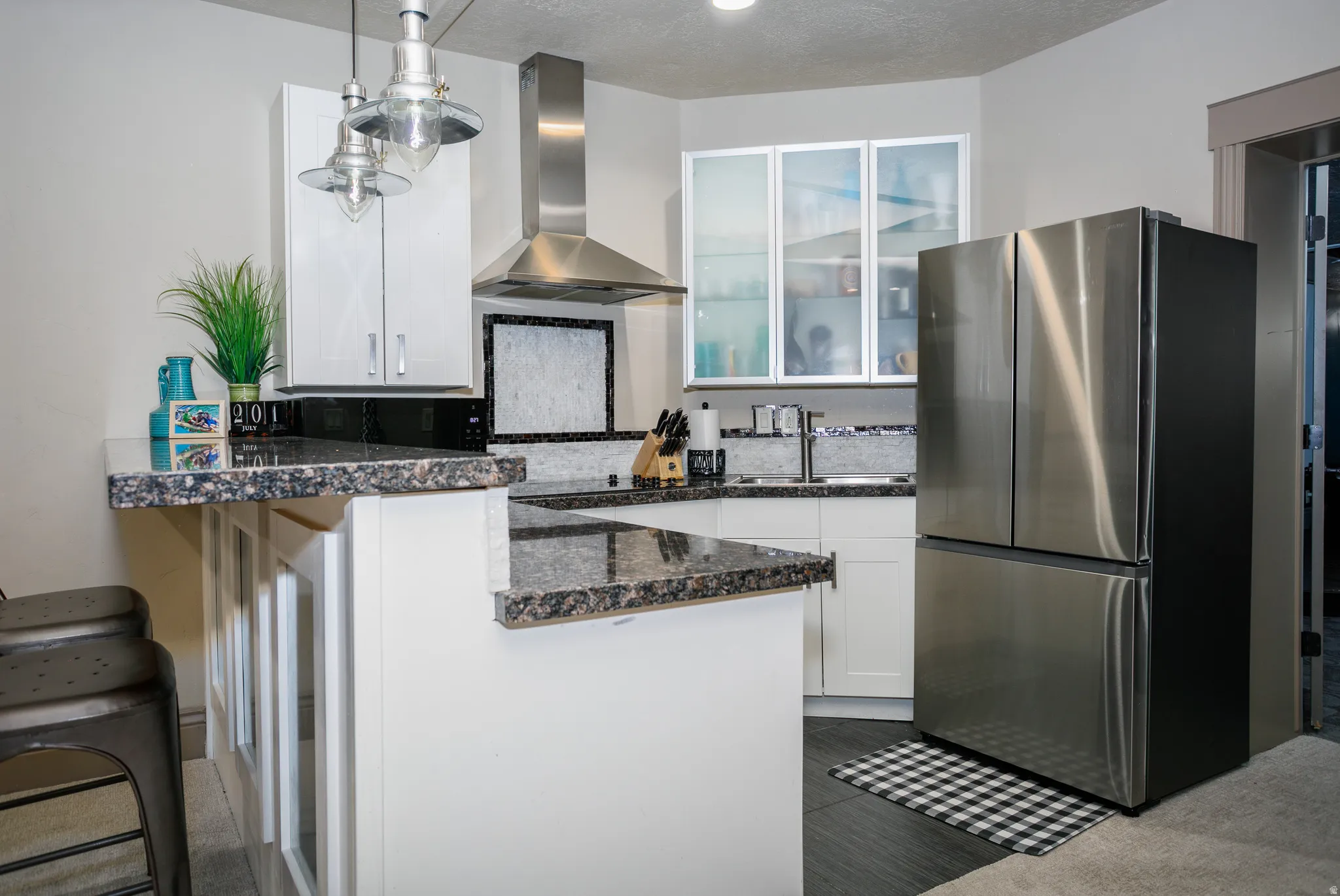 Kitchen featuring granite countertops, white cabinetry, stainless steel appliances, a stainless steel range hood, and pendant lighting