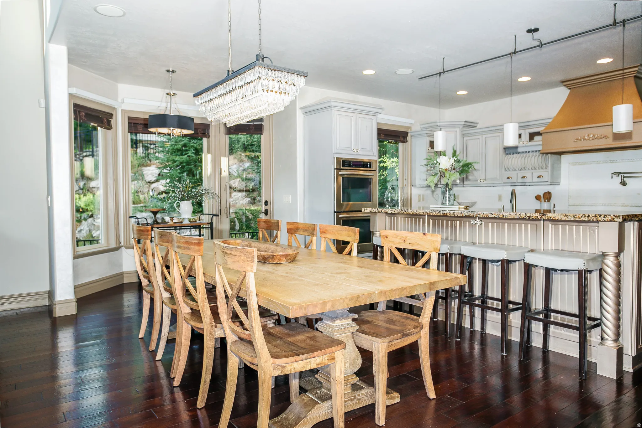 Kitchen and dining area featuring dark wood-finish flooring, a crystal chandelier, recessed lighting, and a kitchen island with beadboard paneling