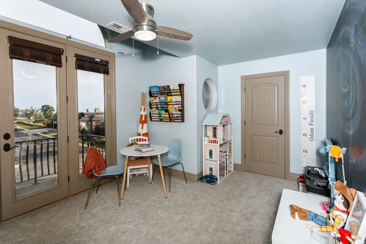 Room featuring light-colored carpet flooring, a ceiling fan with integrated lighting, and a neutral-toned door with dark hardware