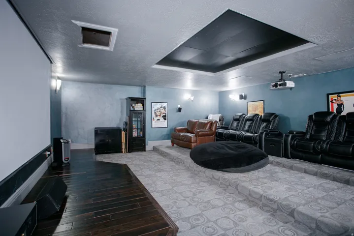 Dedicated theater room featuring tiered seating platforms and a large projection screen