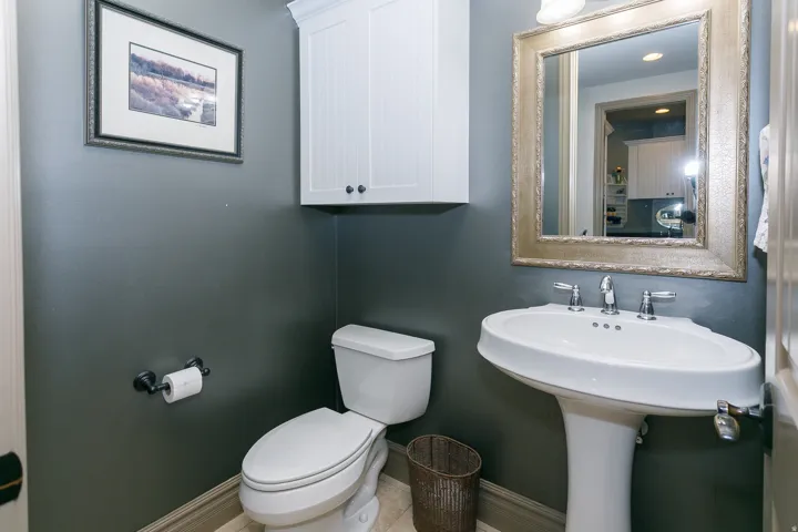 Pedestal sink with chrome faucet, complemented by a decorative framed mirror