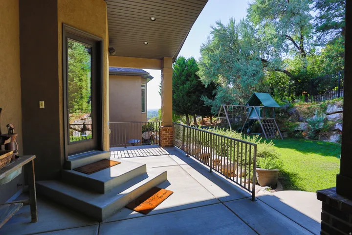 Covered patio featuring concrete flooring, a full-light exterior door, and a black metal railing