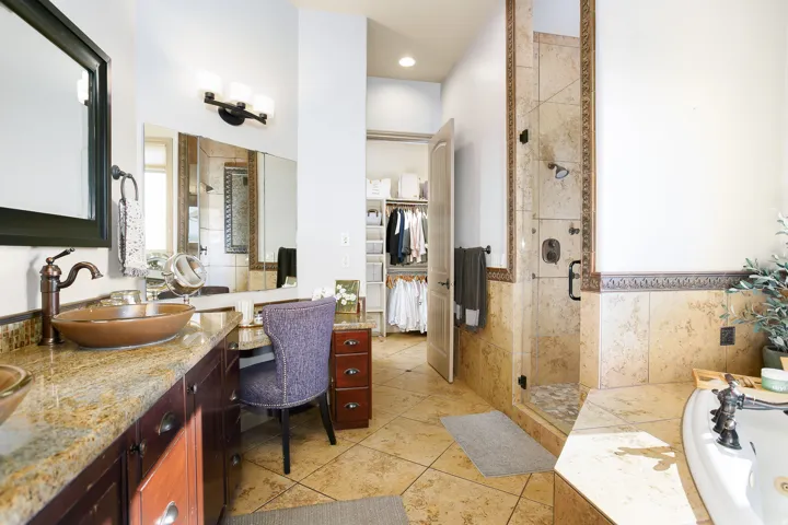 Bathroom featuring a built-in vanity with a granite countertop and vessel sink, a tiled shower with a glass enclosure, a built-in bathtub, and a closet with custom organizational shelving