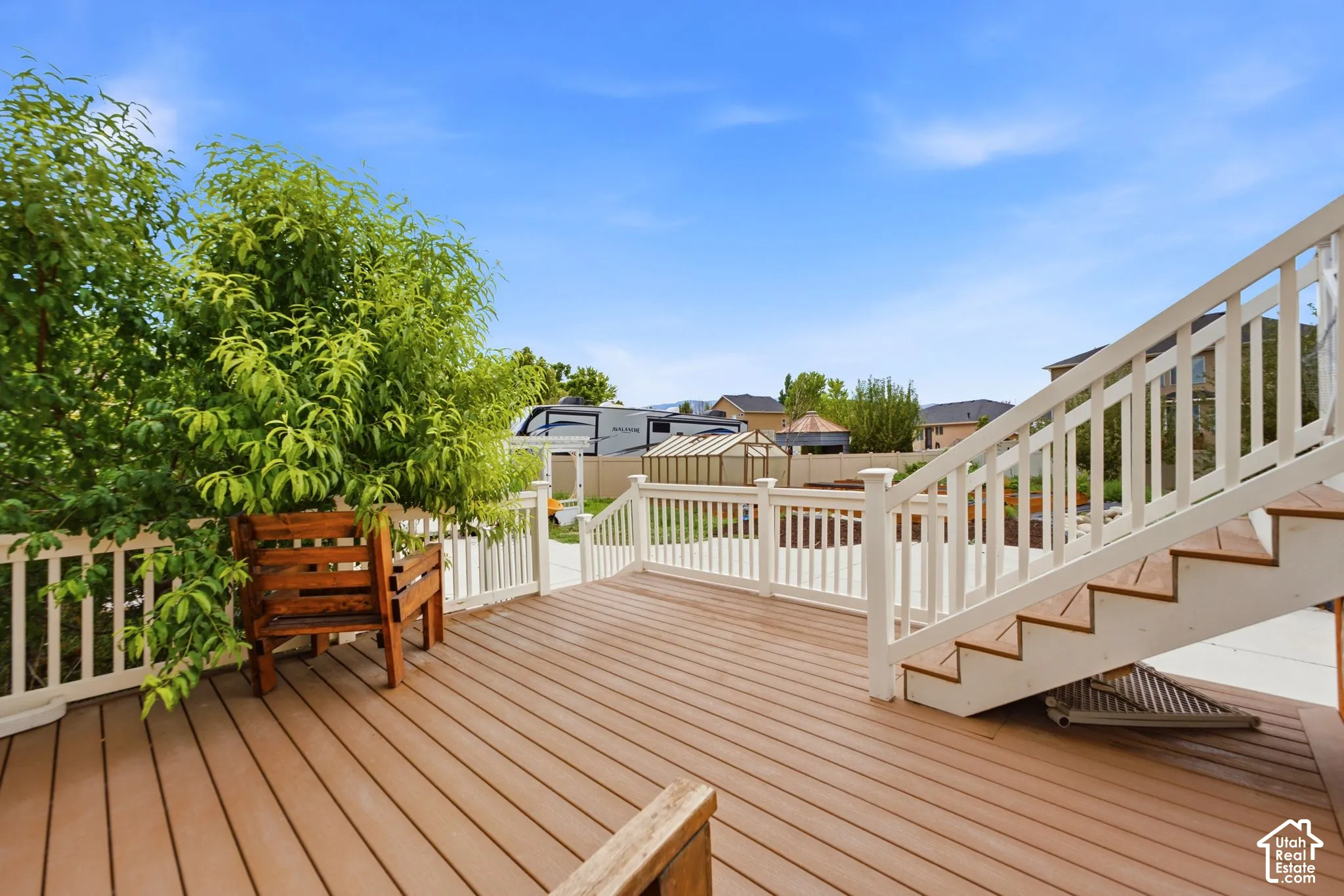 Spacious outdoor deck featuring wood-finish composite decking, white railing, and exterior staircase