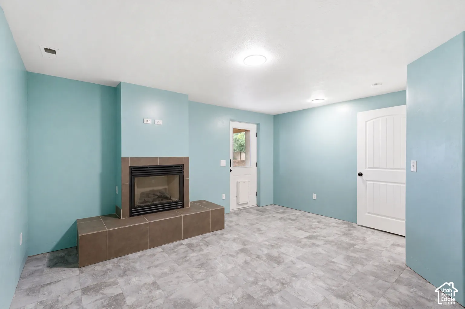 Interior space featuring a tiled fireplace with hearth, light-toned walls, recessed lighting, and a white paneled door
