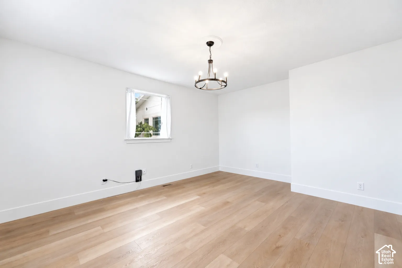 Light wood-finish flooring, white walls, and a multi-light chandelier with ceiling medallion