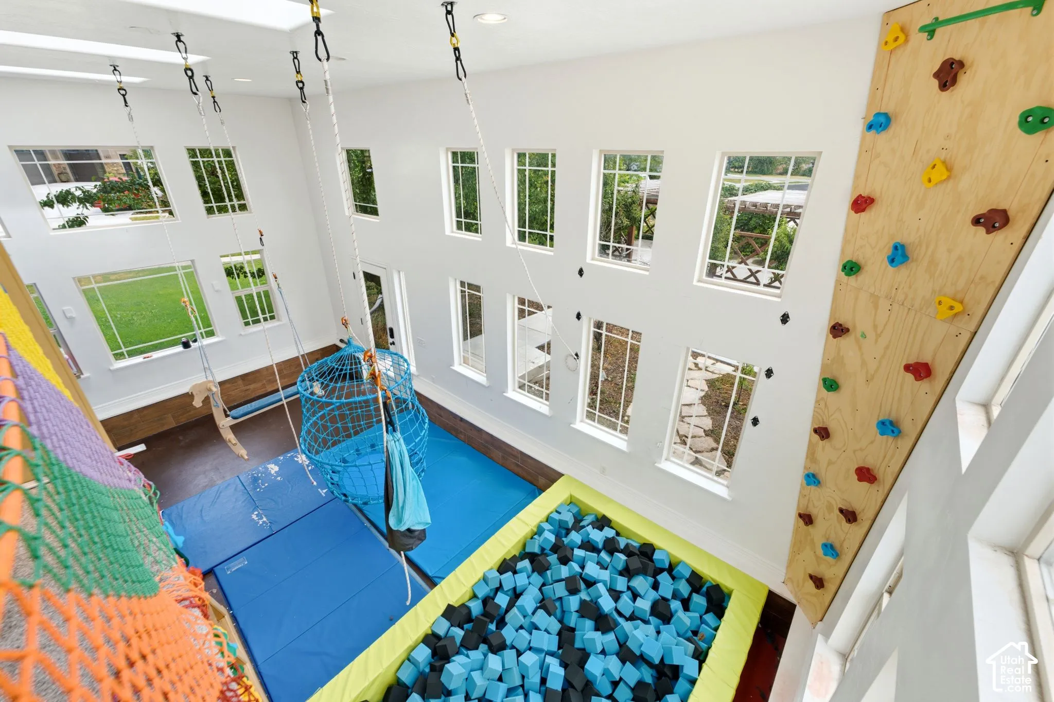 Two-story recreation room featuring a climbing wall, integrated foam pit, and multiple swings