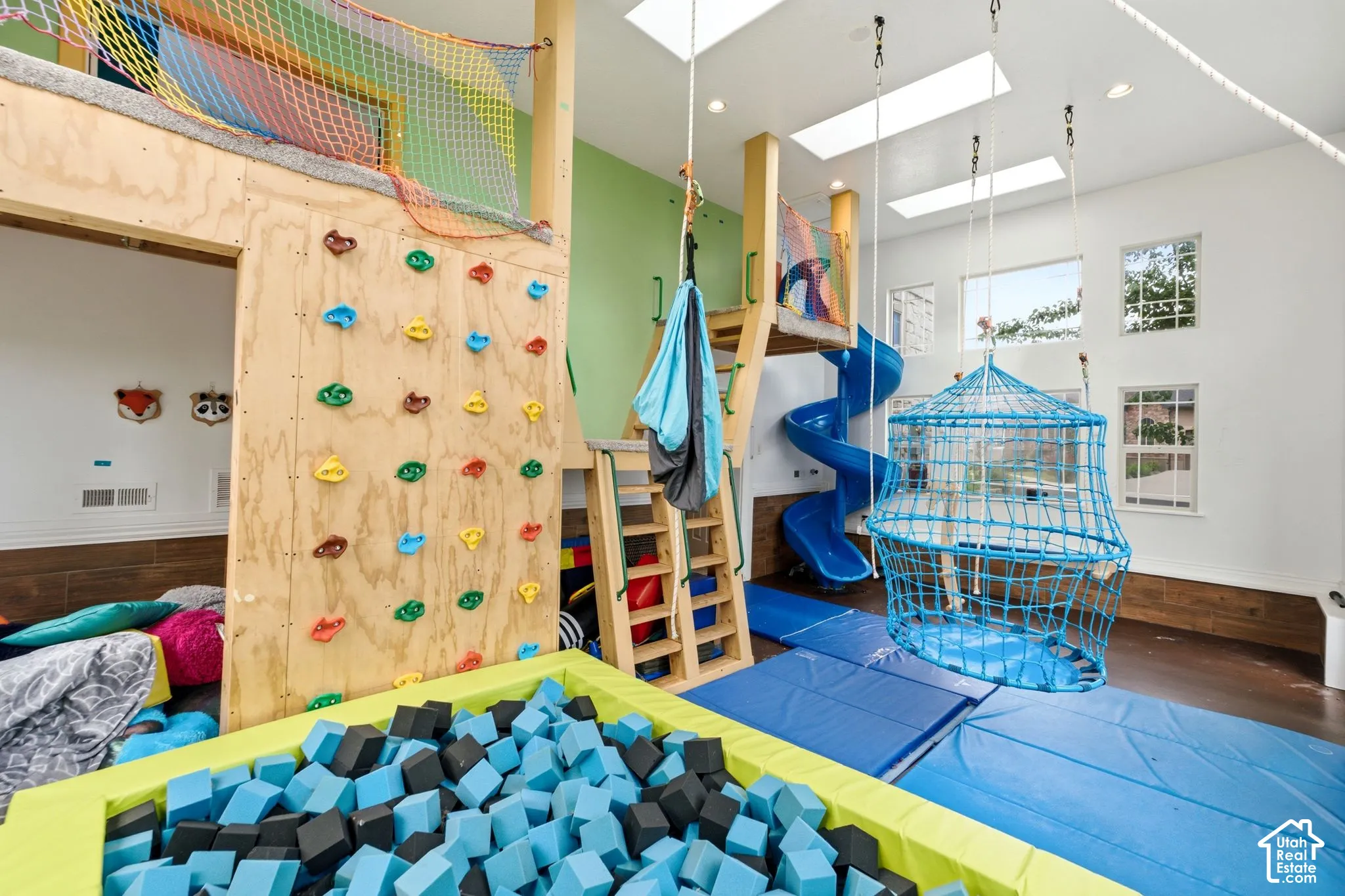 Recreational room featuring a rock climbing wall, spiral slide, and foam pit