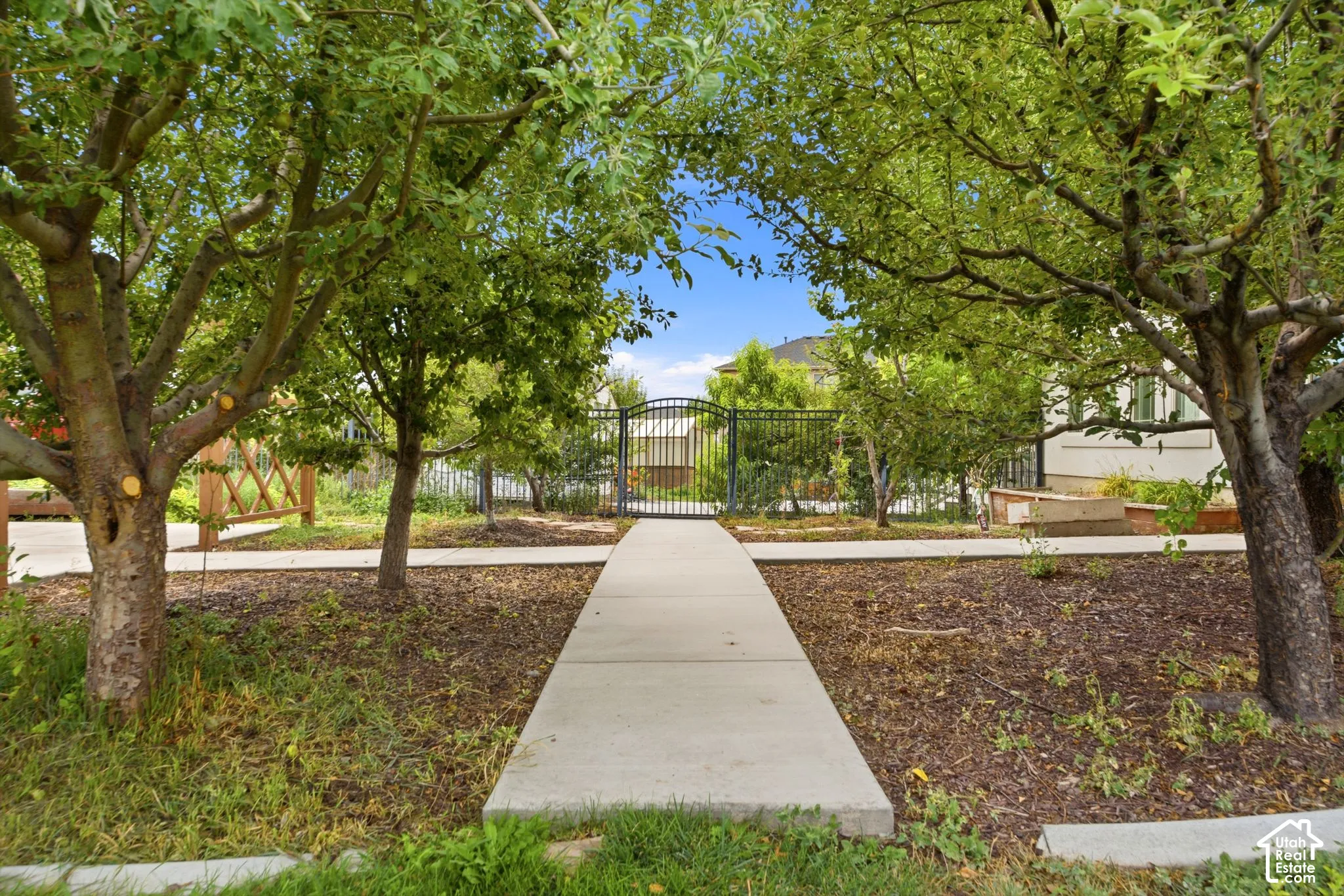 Landscaped pathway leading to a wrought iron gate