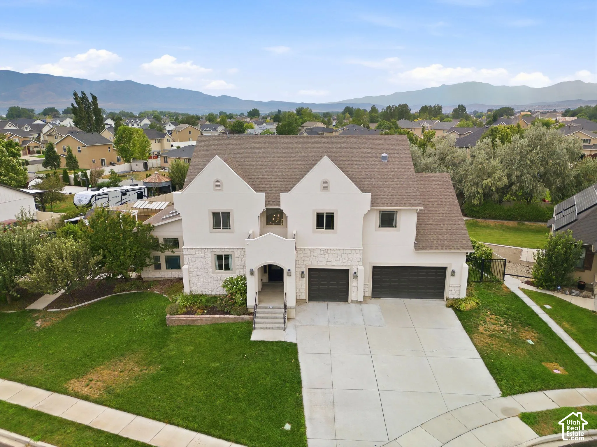 Stately residence showcasing a multi-gabled roofline, stone and stucco facade, and a prominent arched entry
