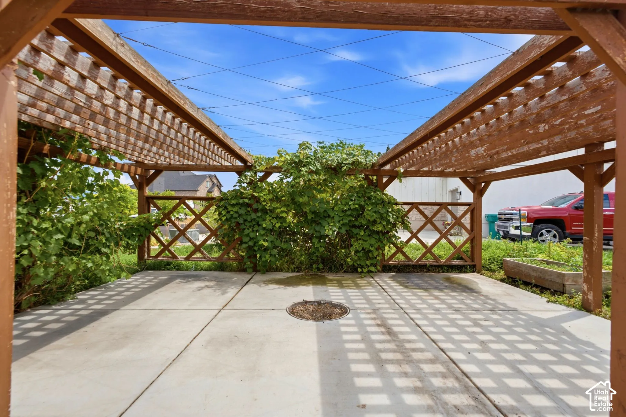 Paved patio area featuring an overhead wood pergola structure