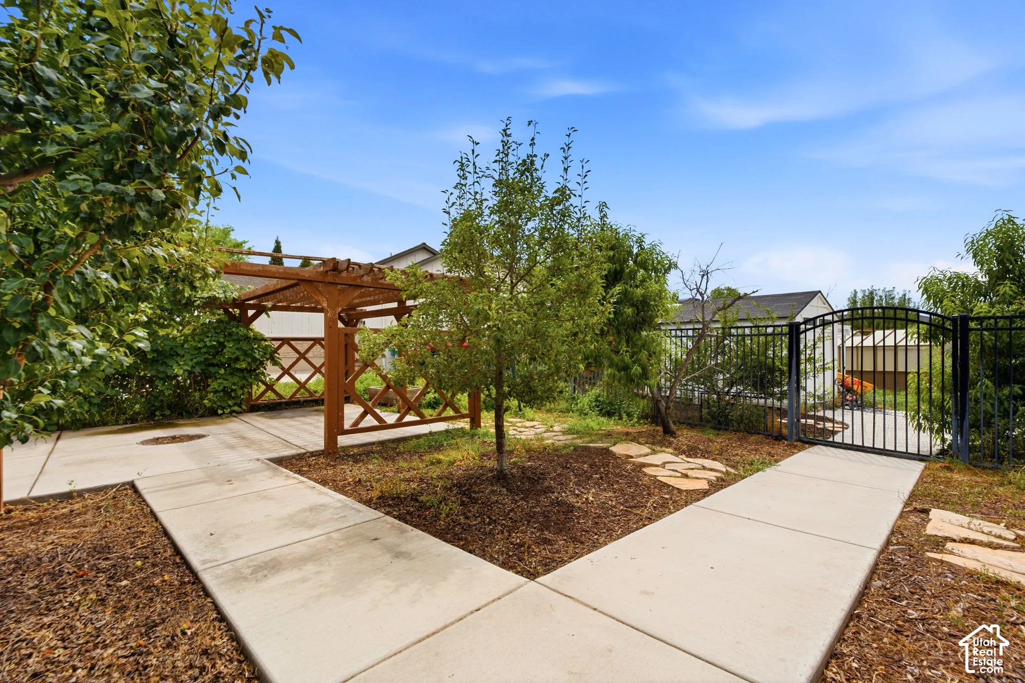 Landscaped outdoor area featuring a wooden pergola and mature trees