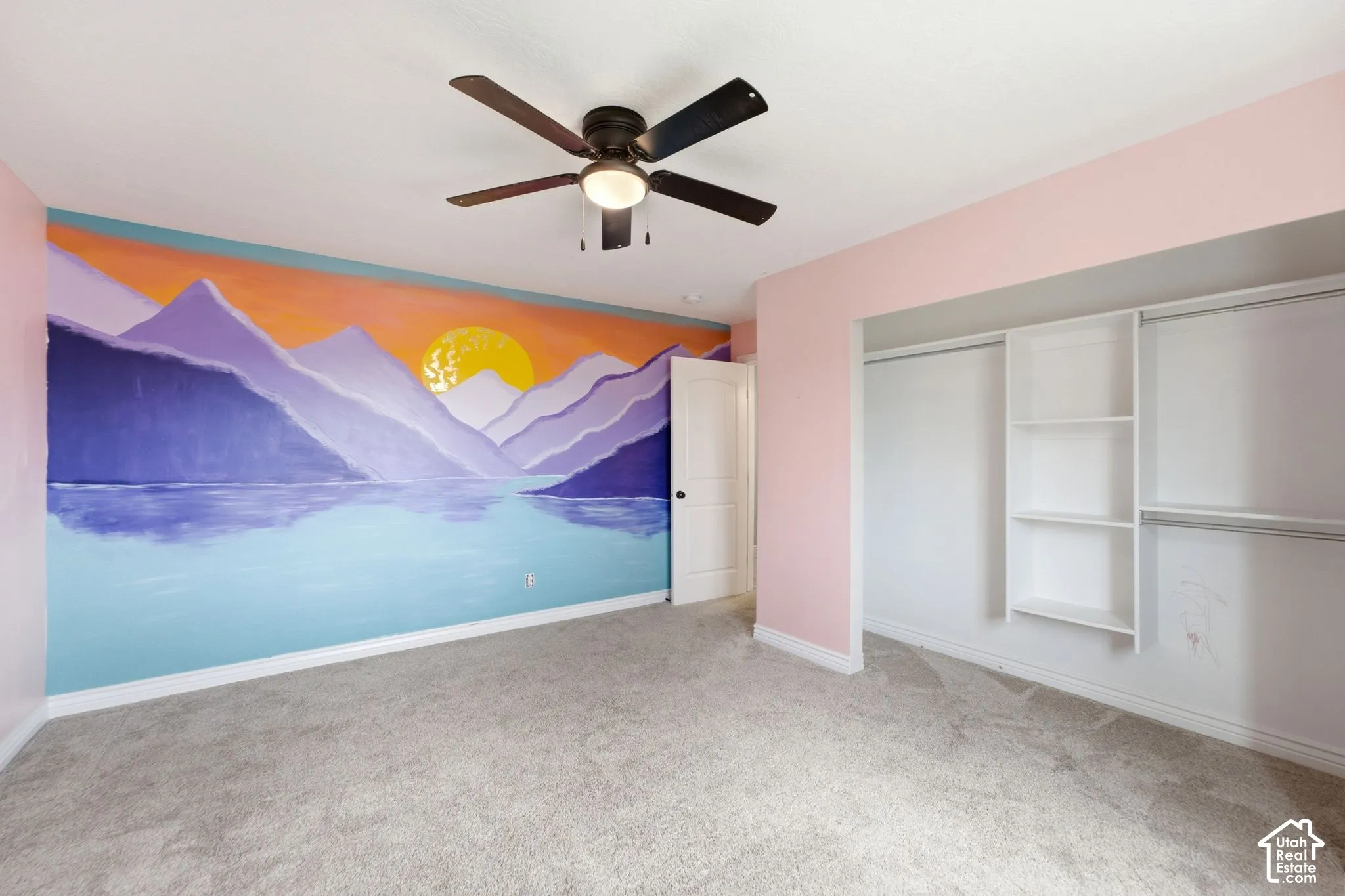 Room featuring a colorful mural wall, ceiling fan with integrated lighting, soft carpet flooring, and a built-in closet system with shelving and hanging rods