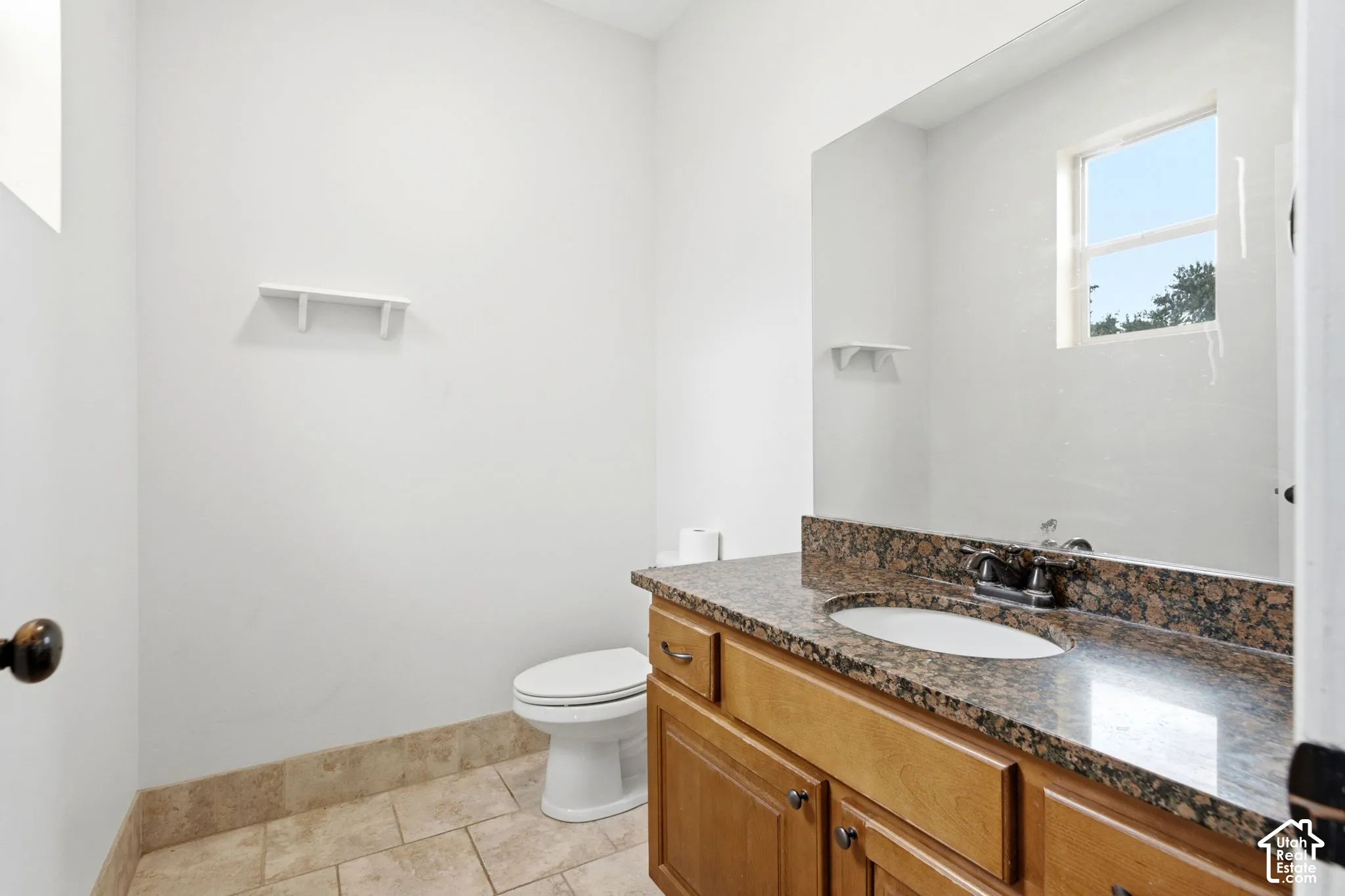 Bathroom featuring a wood vanity with an integrated sink, granite countertop, and a large wall-mounted mirror