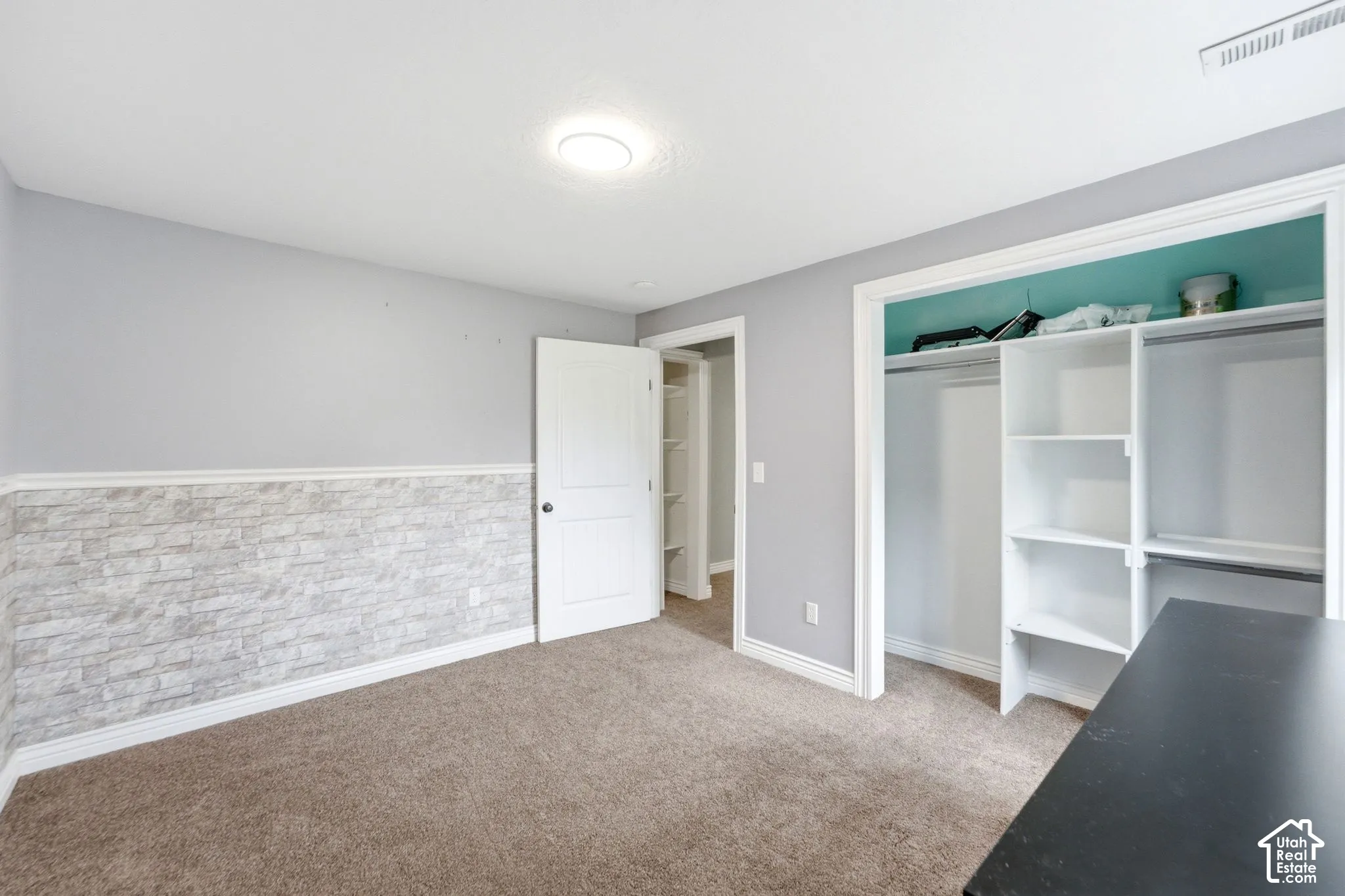 Carpeted room featuring a stone veneer wainscoting, light gray walls, and a white paneled door
