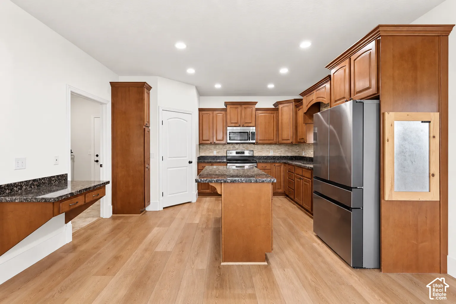 Wood-finish flooring, recessed lighting, wood cabinetry, stone countertops, and stainless steel appliances