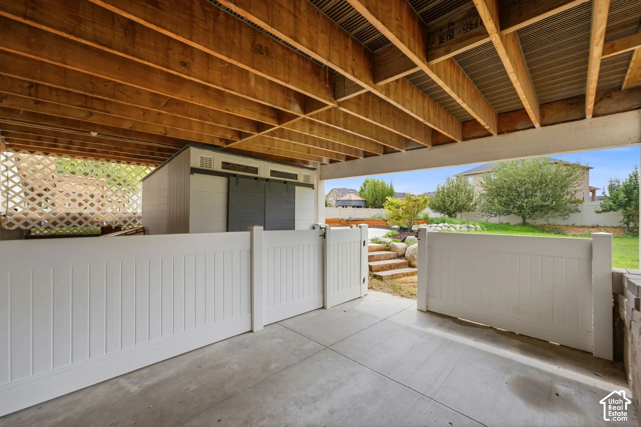 Covered concrete patio area featuring exposed wood ceiling joists
