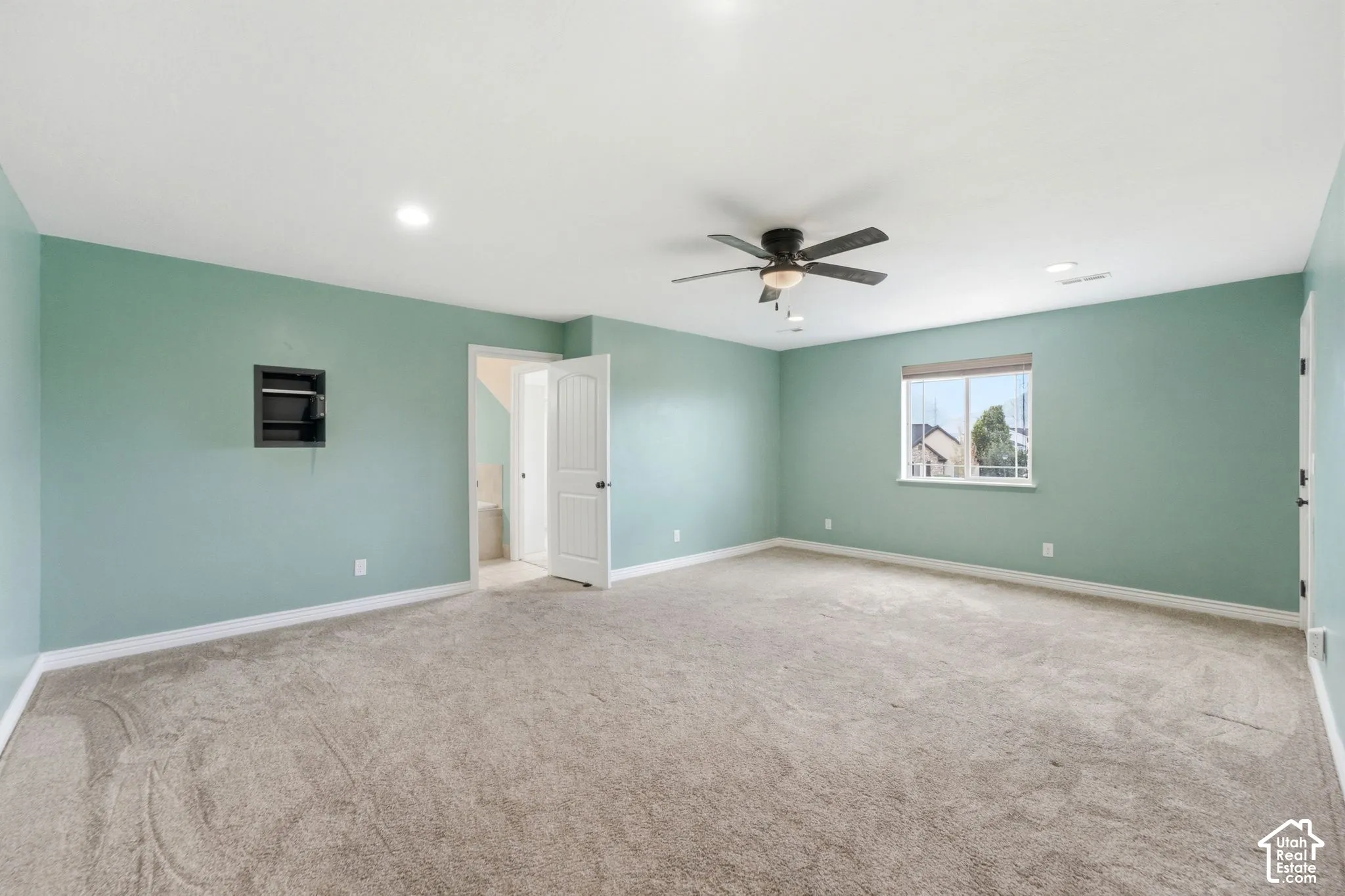 Spacious room featuring light green walls and neutral-toned carpet