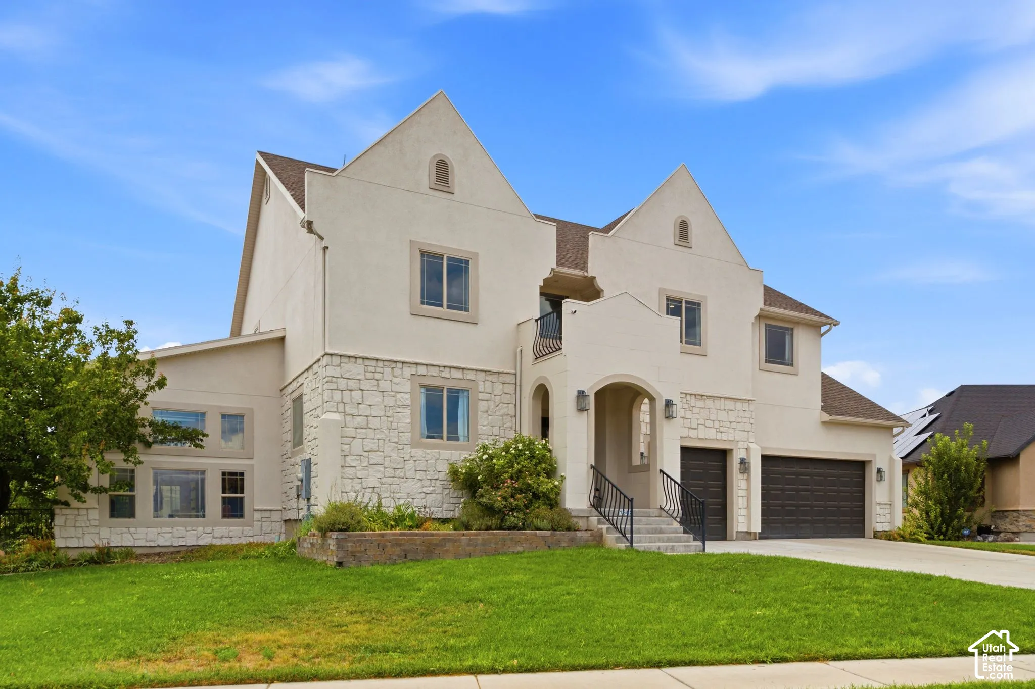 Stucco and stone exterior featuring multiple gables and a covered entry