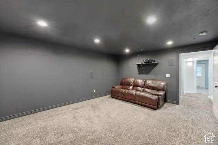 Dedicated media room featuring dark gray walls and ceiling, recessed lighting, wall-mounted speakers, and plush carpeting