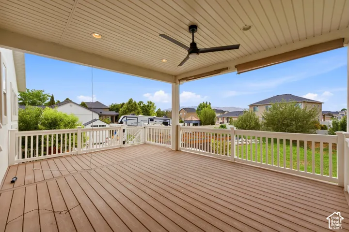 Expansive covered deck featuring composite wood-finish decking, white railing, recessed lighting, and a ceiling fan