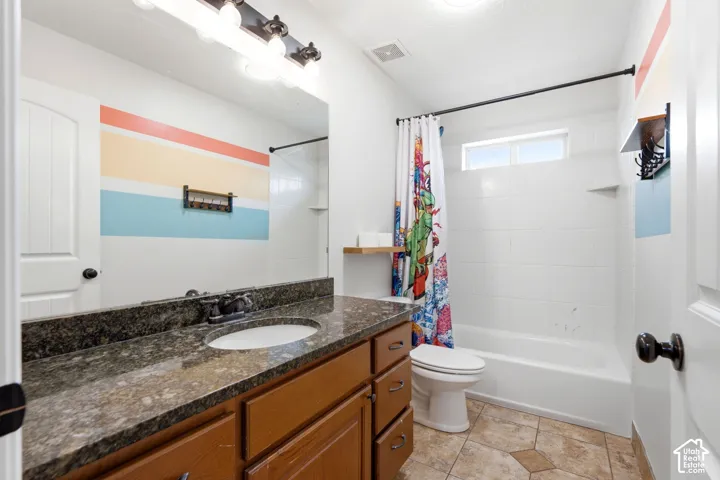 Bathroom featuring a spacious vanity with granite-style countertop, integrated sink, and wood-finish cabinetry
