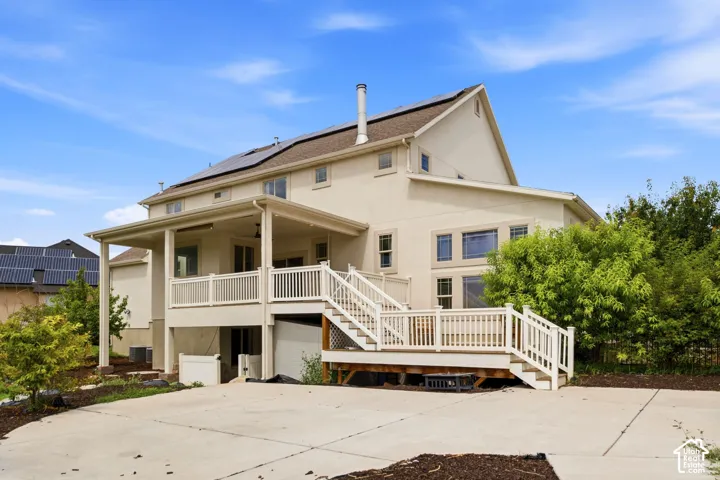 Rear exterior featuring a multi-level deck with white railings, a covered patio, and solar panels on the roof