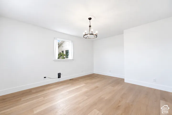 Light wood-finish flooring, white walls, and a multi-light chandelier with ceiling medallion