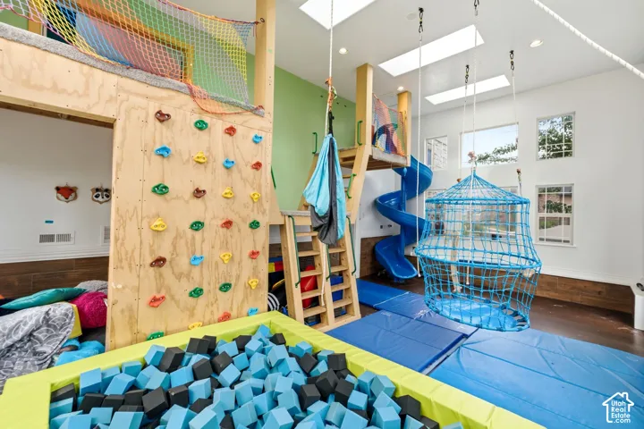 Recreational room featuring a rock climbing wall, spiral slide, and foam pit