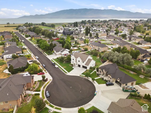 Aerial perspective showcasing a residential neighborhood with a mountain and body of water backdrop