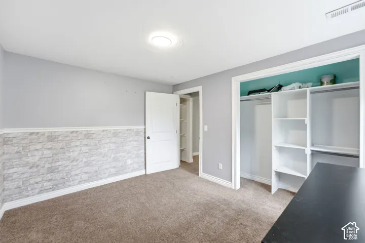Carpeted room featuring a stone veneer wainscoting, light gray walls, and a white paneled door